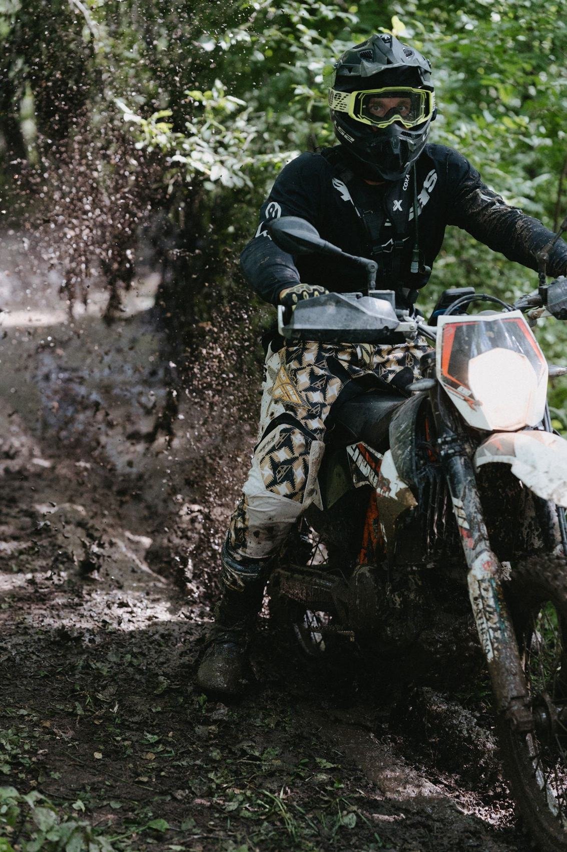 Motociklininkas taško purvą miško kelyje