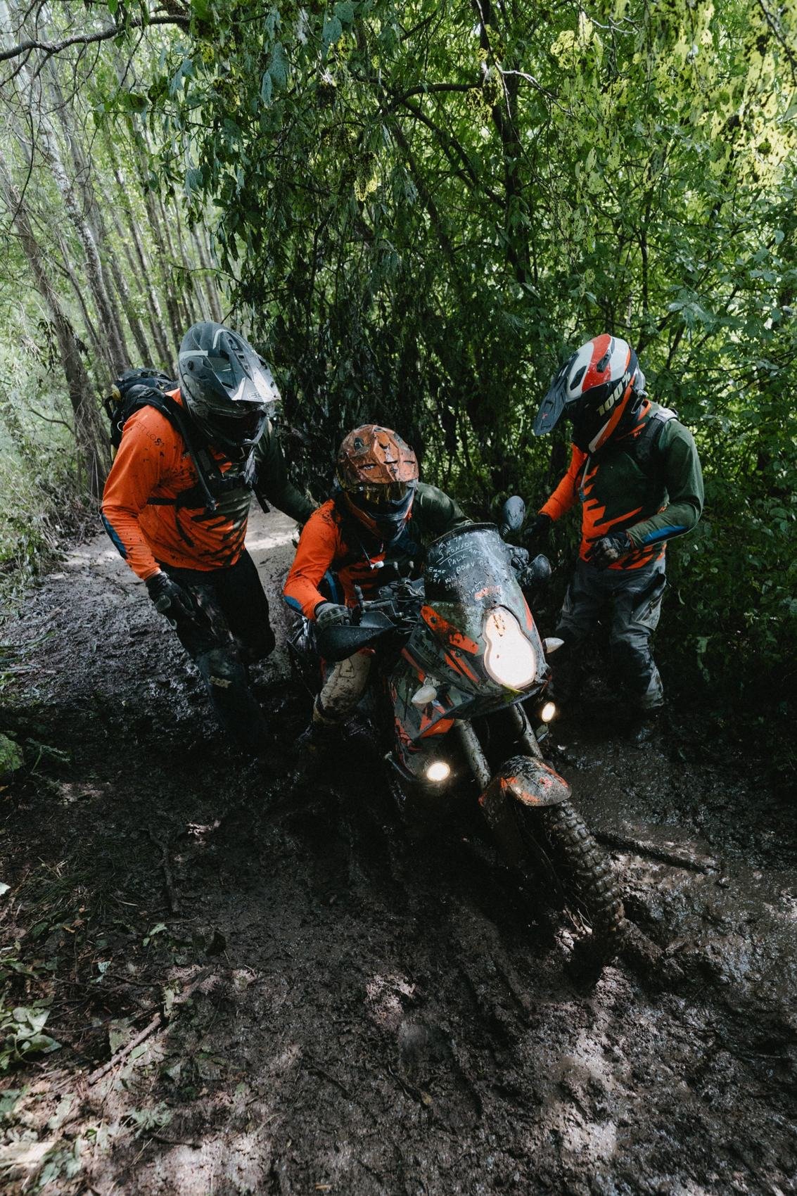 Komanda kartu ištraukia motociklą iš purvino miško ruožo