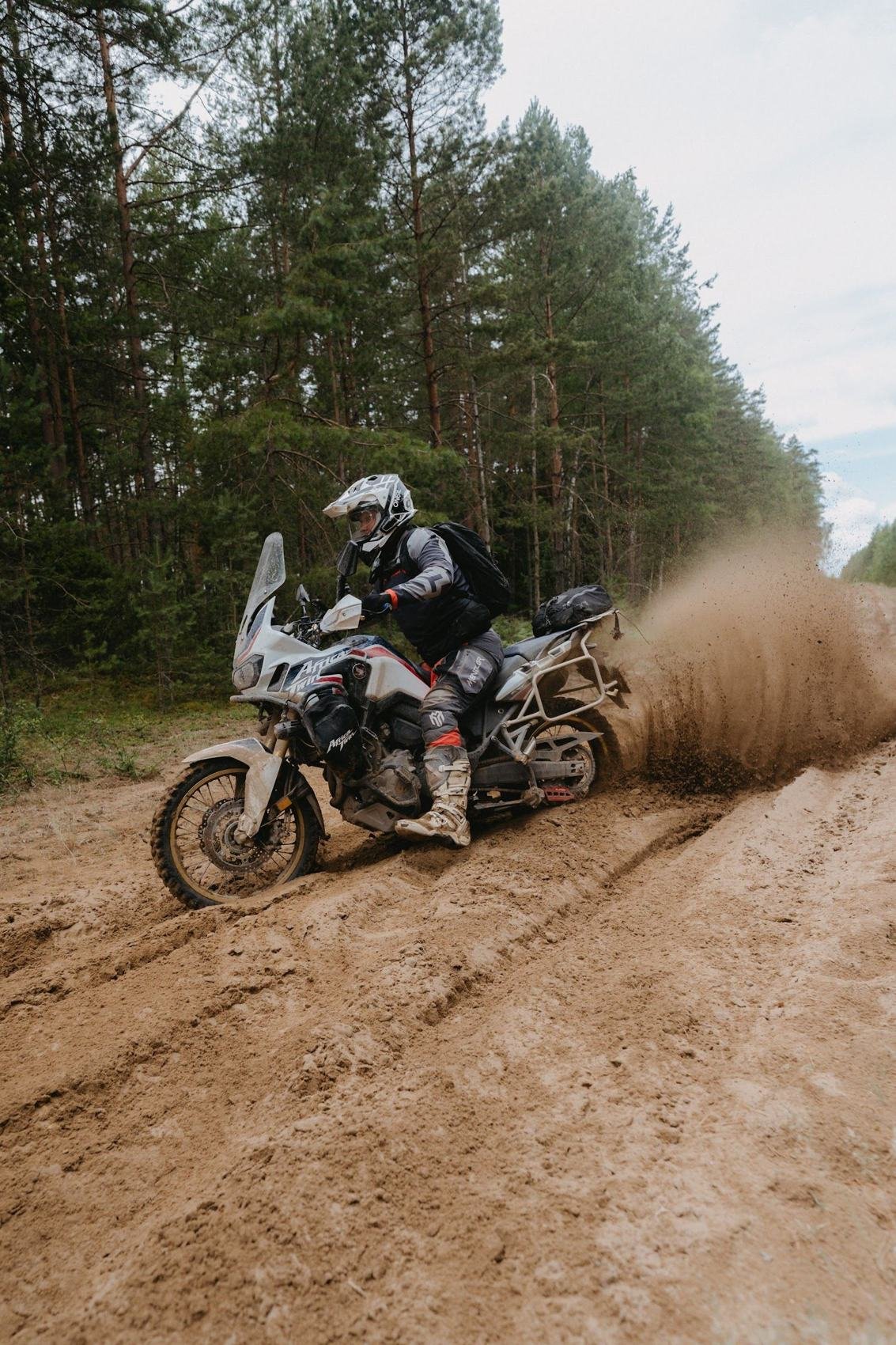 Adventure motociklininkas smėlėtame miško posūkyje